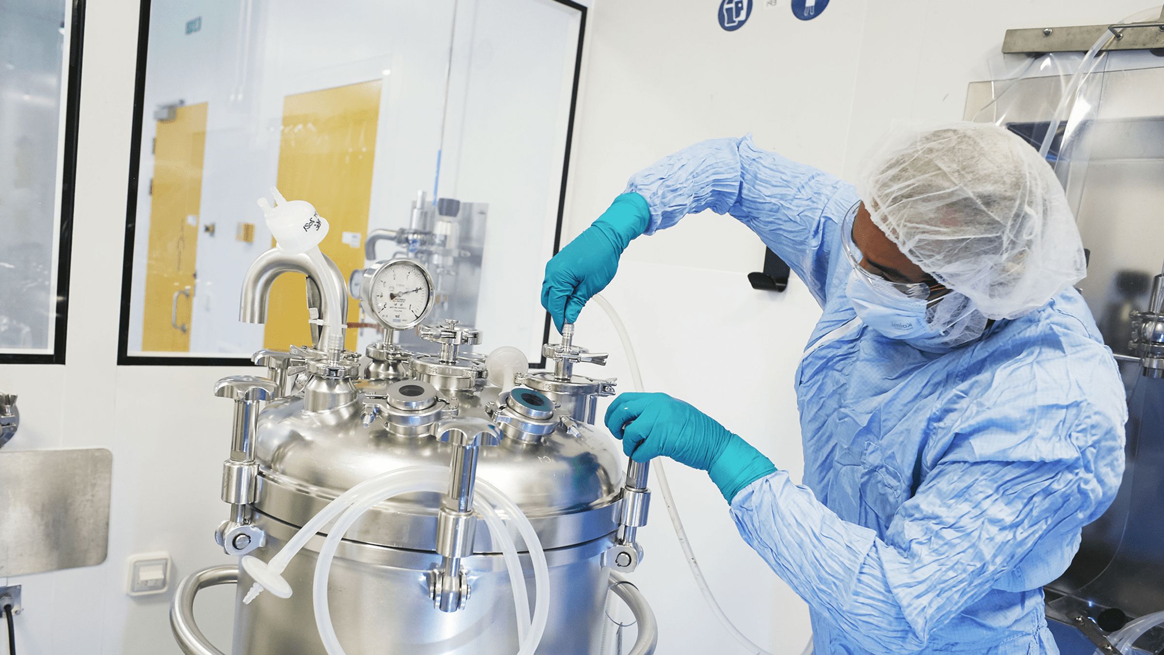 Opérateur en tenue de protection complète manipulant un équipement de production en environnement stérile.