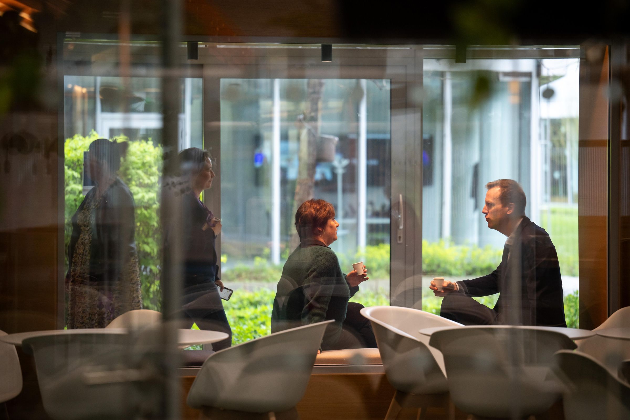 Carole et Pierre en conversation dans un espace de travail moderne avec vue sur l’extérieur.