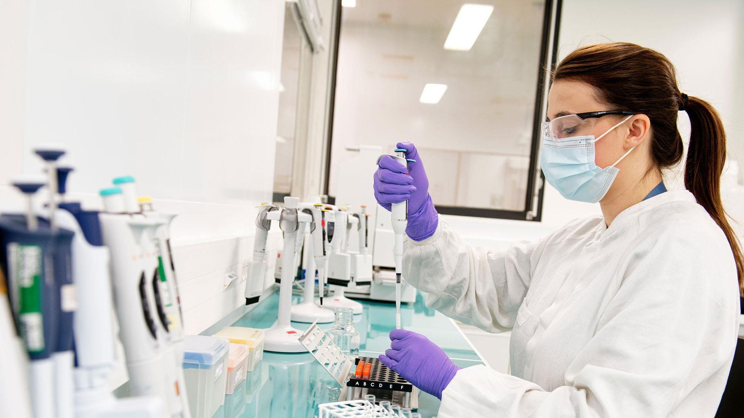 Chercheuse en équipement de protection manipulant une pipette avec des échantillons en laboratoire