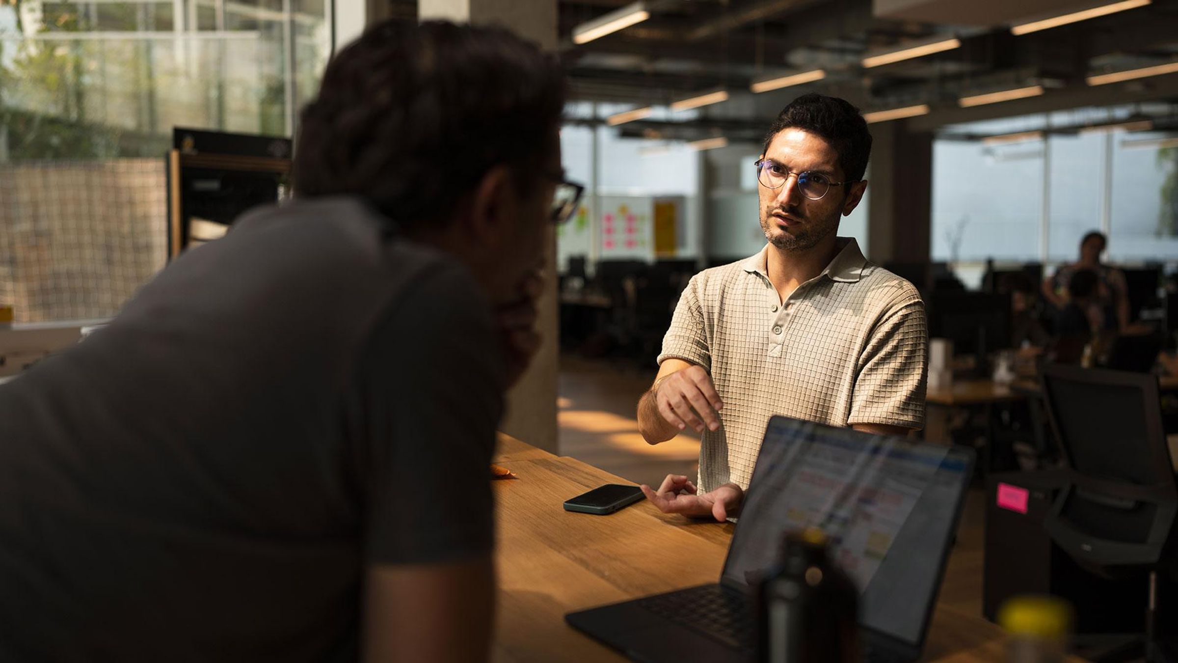 Deux collaborateurs de notre Accélérateur Digital à Paris, en train de discuter, autour d'un ordinateur, dans un open space.