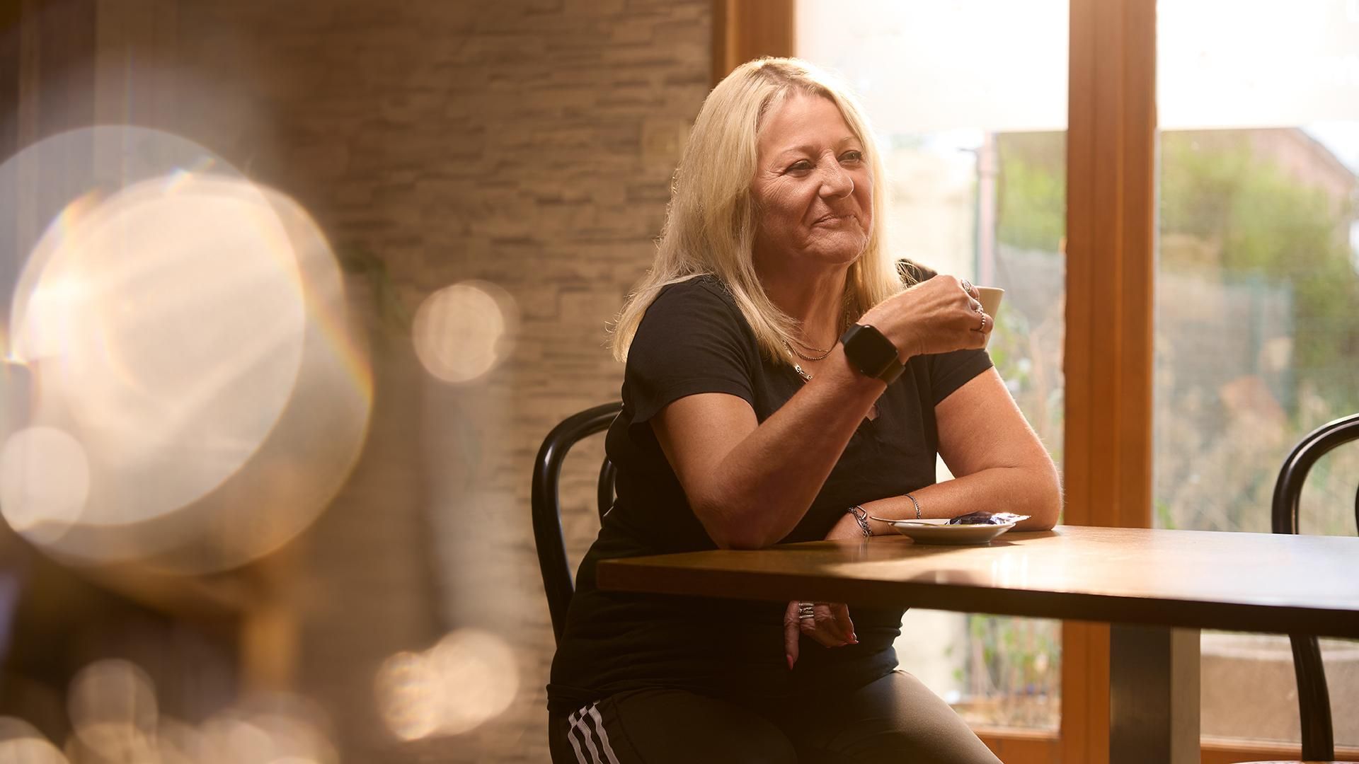 Femme assise à une table tenant une tasse dans un café
